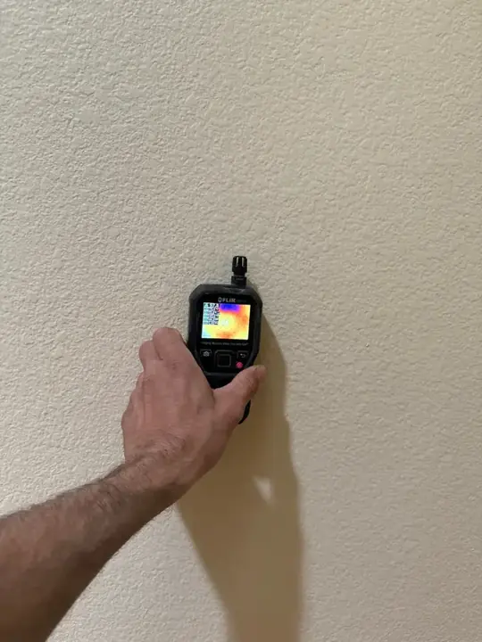 Moisture meter reading a wall during a water damage walkthrough in Cedar Park