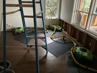 Air movers drying a room with the baseboards pulled during a Cedar Park water damage dry-out