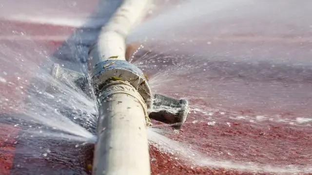 Water spraying from a burst pipe inside a Cedar Park wall